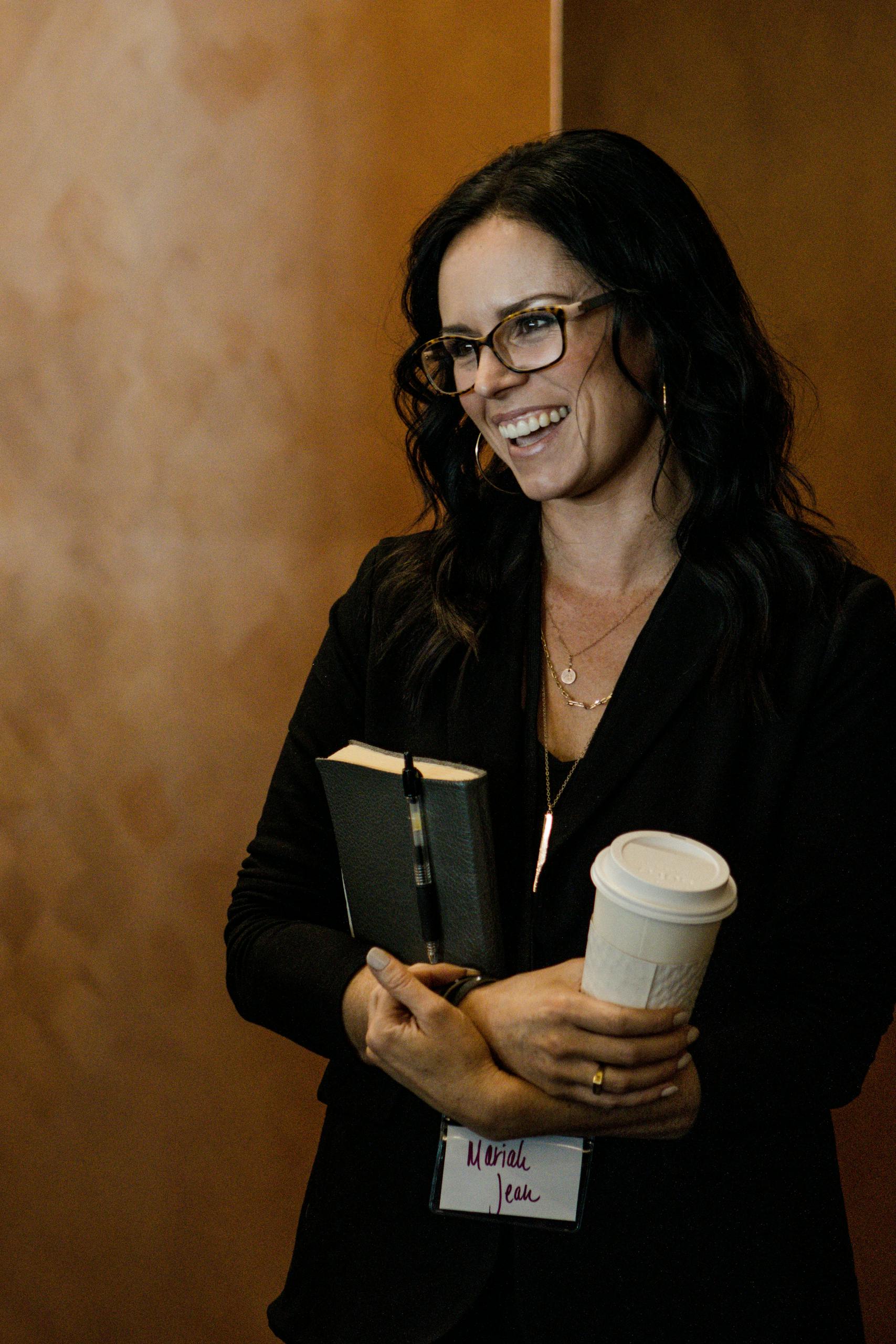 Businesswoman smiling with coffee and notebook at Kansas City event.